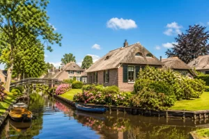 Pittoresk Nederlands dorp met rietgedekte huizen, bloemen en een rustige gracht.